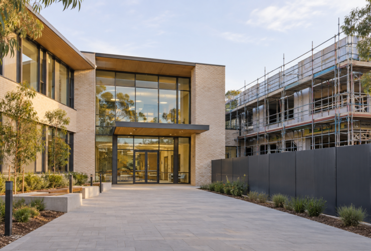 Illustration of a completed building entrance beside an area still under construction, showing staged handover.